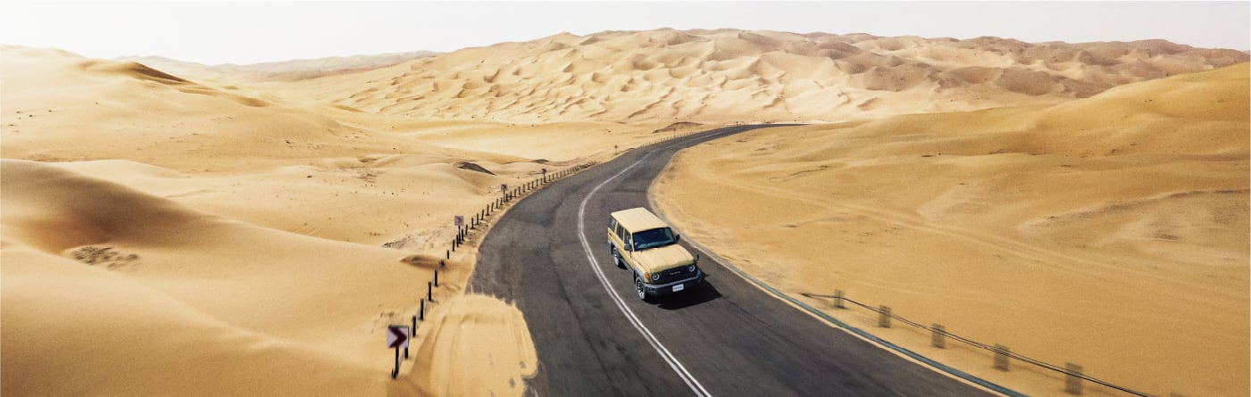 砂漠の中の道路を疾走するランドクルーザー70